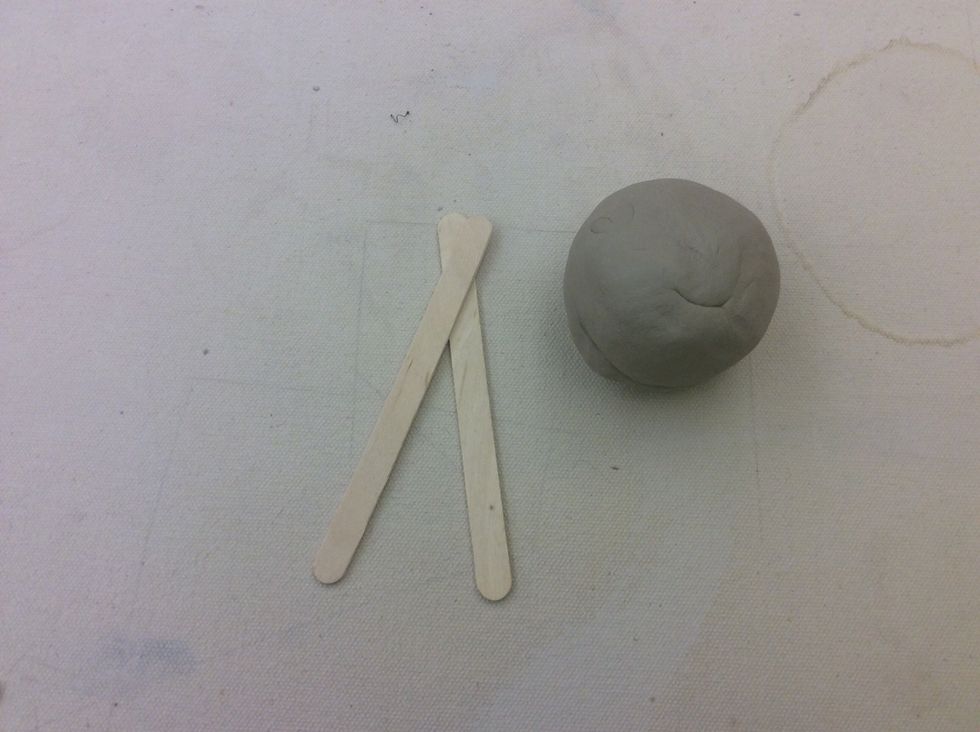 You are going to need two Popsicle sticks and a ball of clay that is slightly larger than a golf ball.
