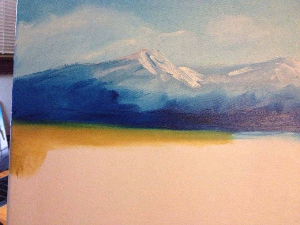 You can add a little snow at the top if you want, using a dab of white and an index finger that barely touches the mountain top. Next, clean your hand and grab some ochre and start your land.