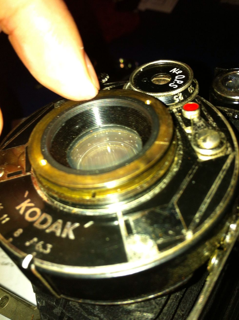 You can now see the brass lens ring. Unscrew this gently with your hands or your rubber mat. Don't use a tool that will scratch your glass. It's lasted 80-100 years don't ruin it now