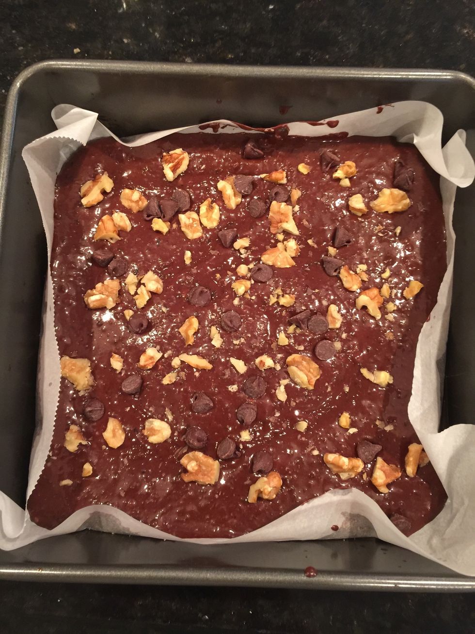 You can spray/ or run your tin with oil or use parchment paper. Then pour batter in the tin. Add your toppings like walnuts and chocolate chips.