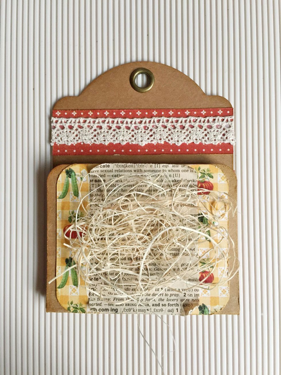 You can start embellishing the seed pocket as shown... I'm using some crochet lace, vintage dictionary papers and shredded wood fibers as add-ons...