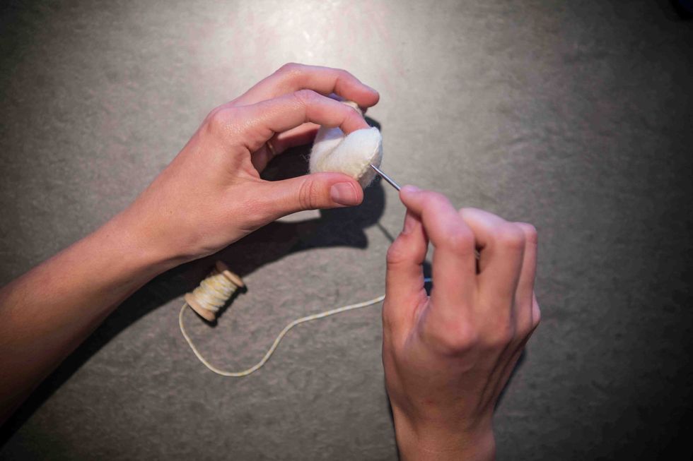 You can string your garland either horizontally or vertically. We are stringing ours horizontally. Stick the needle through a hole on the side.