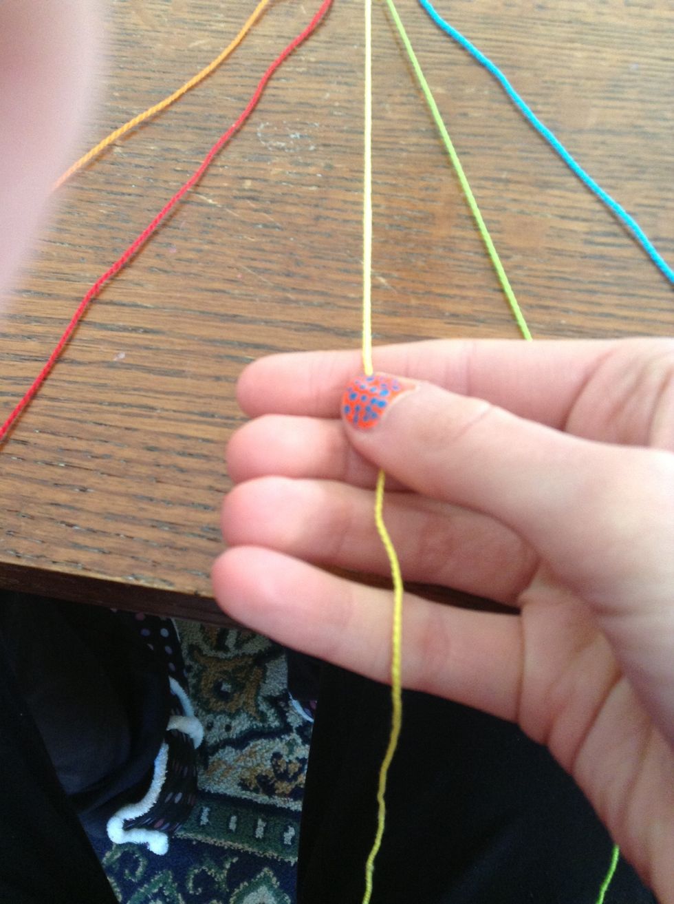 You do the same thing you did with the green string, but from the other side. :) Take the yellow string, and cross over to the right, over the two strings next to it, so that its now in the middle. :)