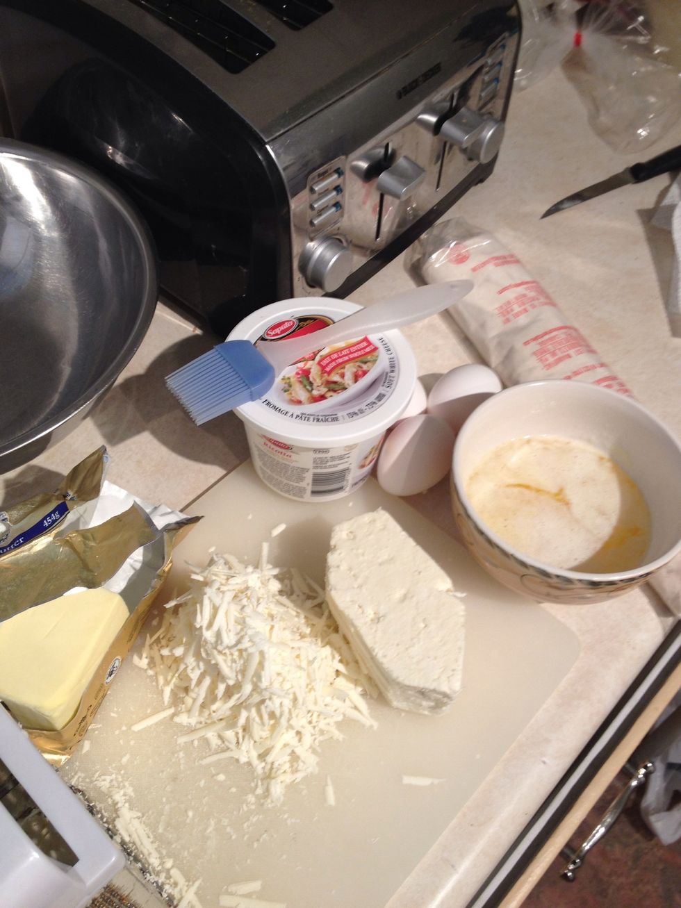 You'll need: 500g of feta cheese, 475g of ricotta, 3 eggs, half a pound of butter, phyllo dough, a little bit of pepper. Cutting board and brush. First you need to grate the feta.