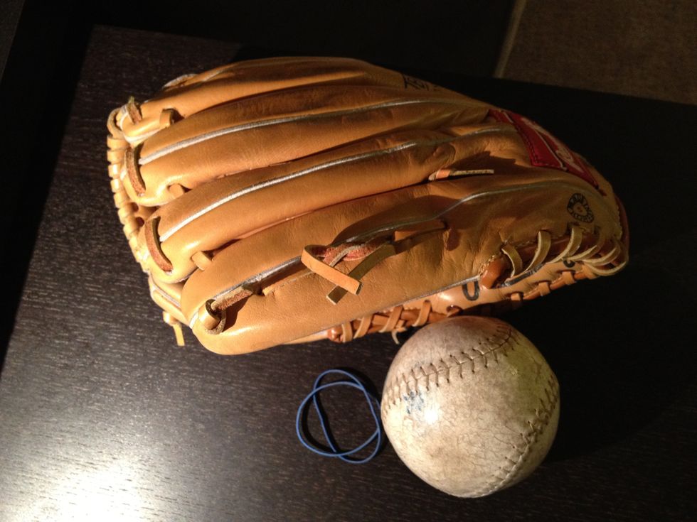 You'll need a glove, a baseball (softball is pictured) and one strong or a couple of normal rubber bands.