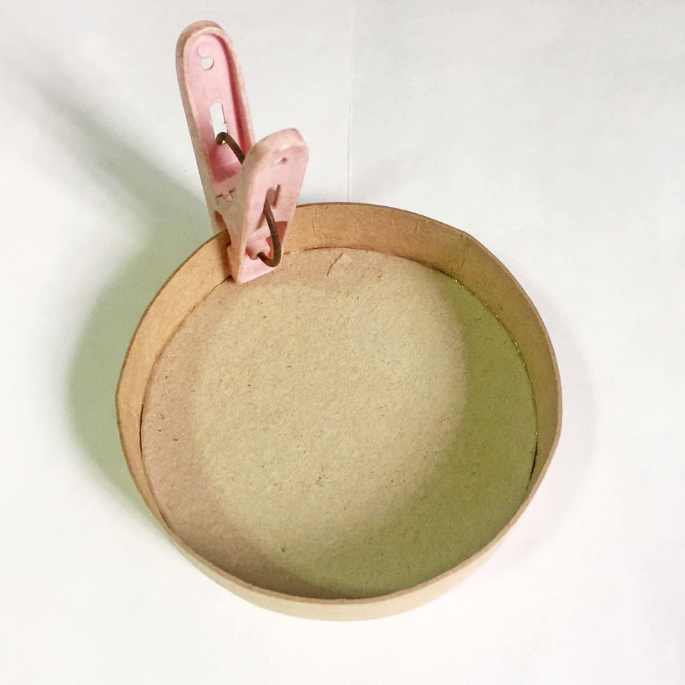 You may find it easier to lay the lid flat and rim it around while adhering the strip. Trim off the excess strip and secure the edges using a clothes peg.