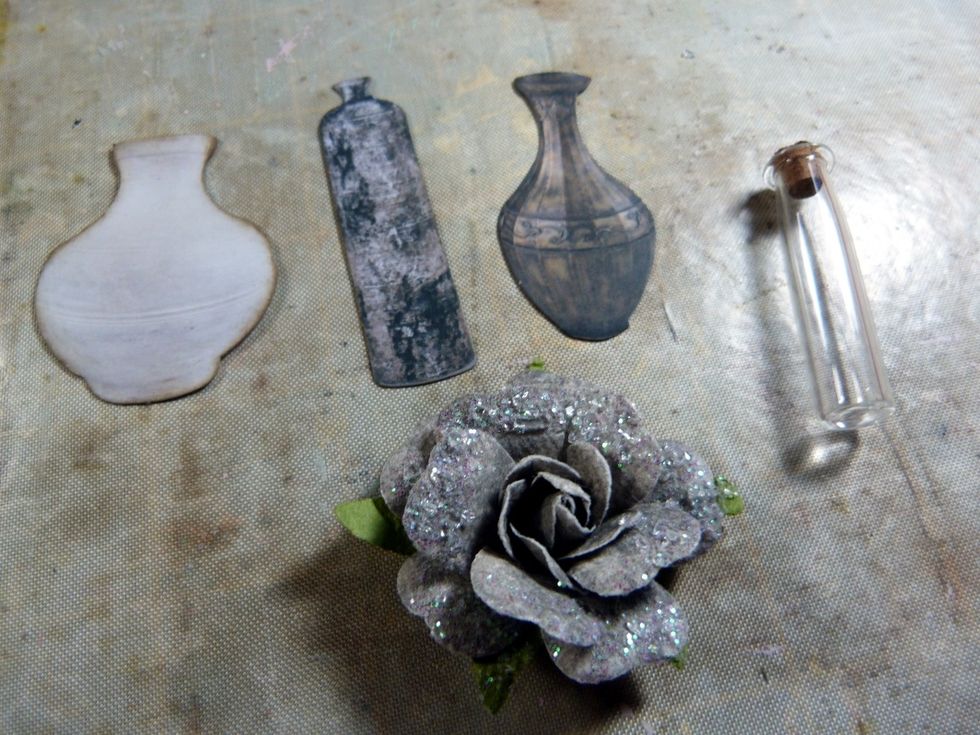 You need these bottles & die cut vases from the Prima ephemera, ink edges. Also one more grey flower. Glue a piece of lace to the bottom inside 'shelf' in between where you have put the cotton reels.