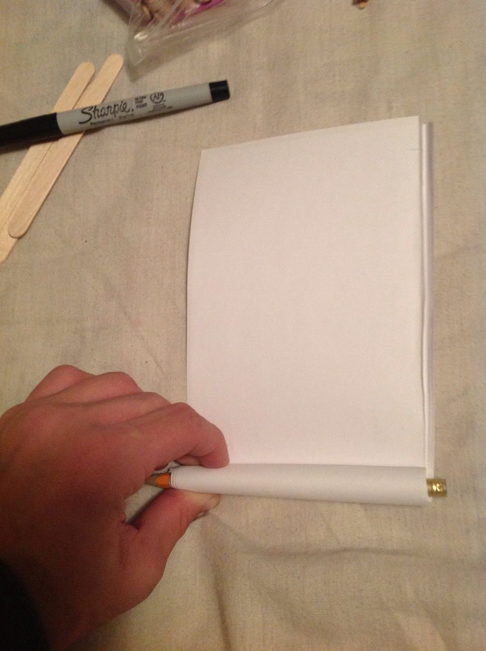 You need to then take a pencil and start rolling the four sheets around the pencil to make it into a tube.