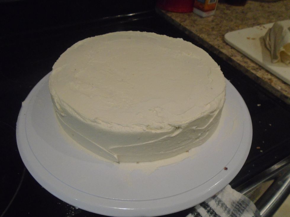 You will have a rim of frosting at the top of the cake, level it out with the offset spatula. Smooth out the top of the cake using the offset spatula.