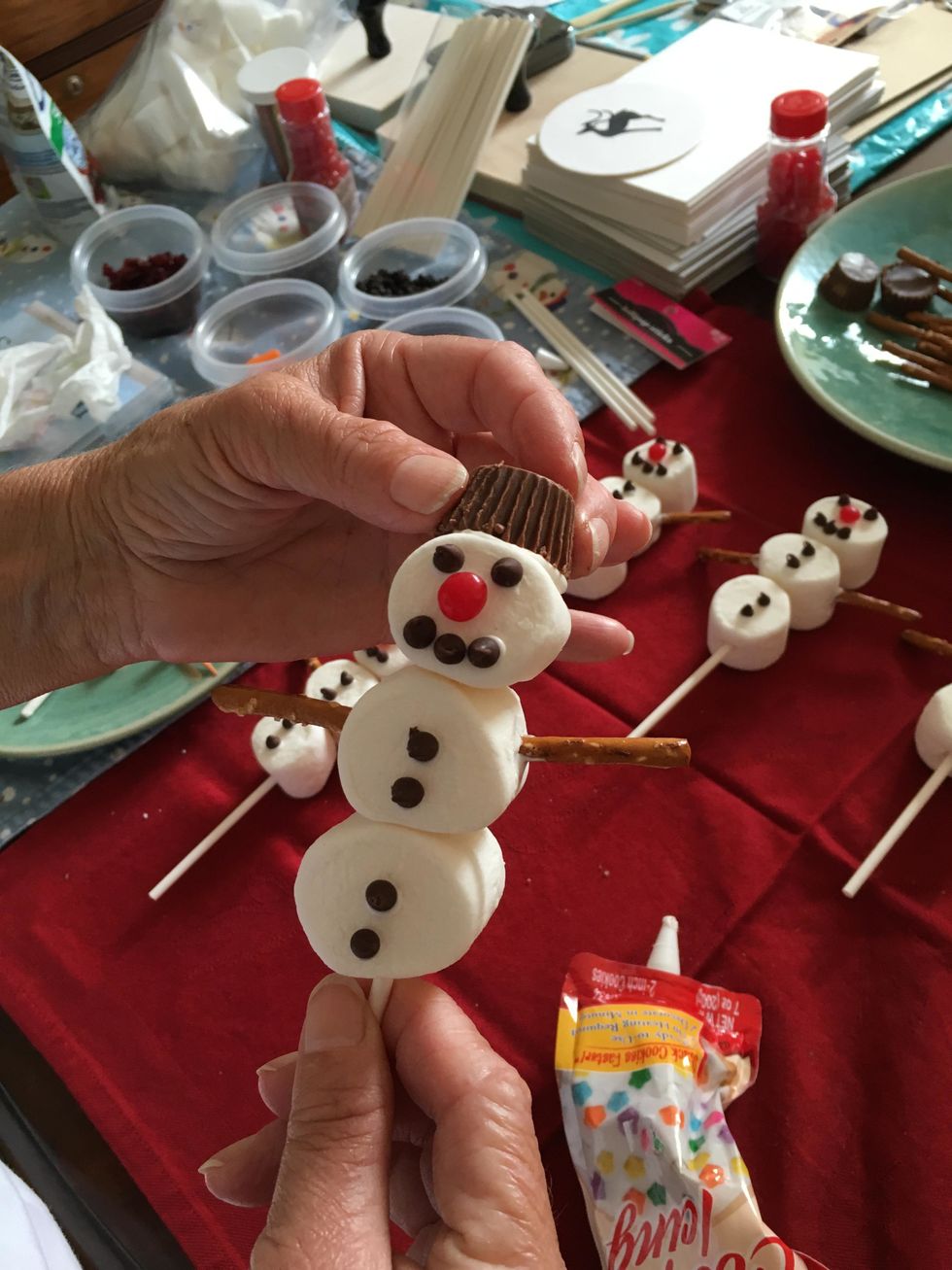 You will have to hold the hat in place for a minute.  Lay the snowman flat to allow the cookie icing  to harden.