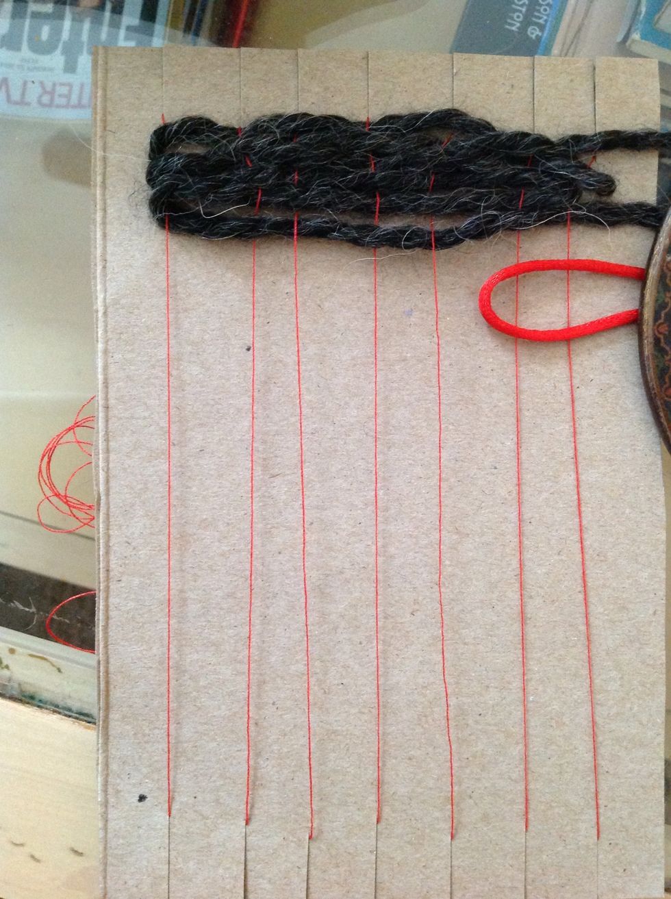 You will hold the folded part of the string tightly and begin by weaving OVER TWO warp strings.