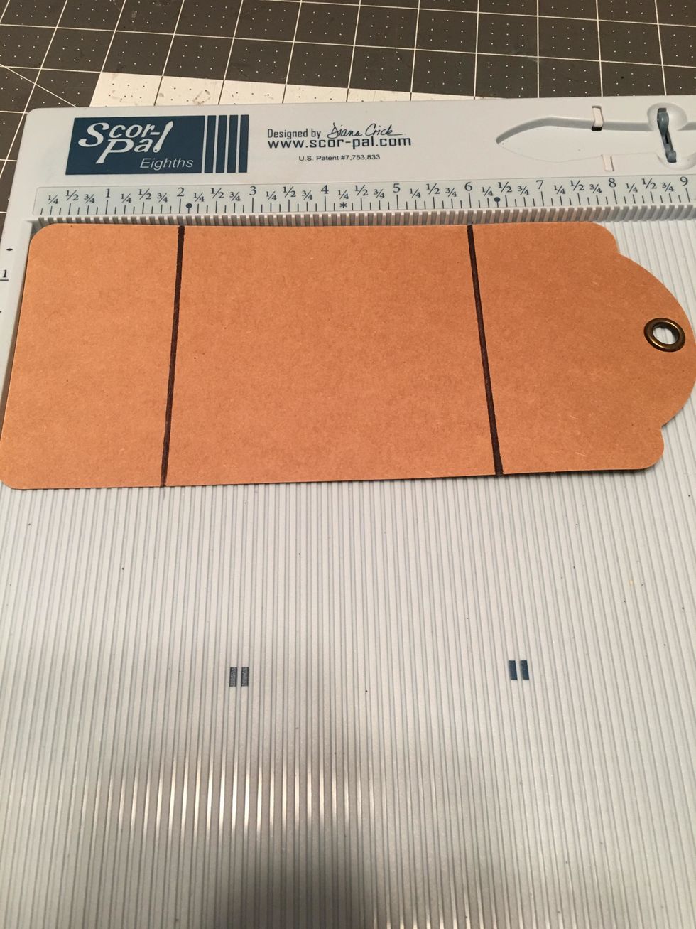 You will need one Graphic 45 Tag from their Large Tag Album to create a closure. Score the long side of the tag at 2" and 6". Measure and score from the rounded bottom edge of the tag.